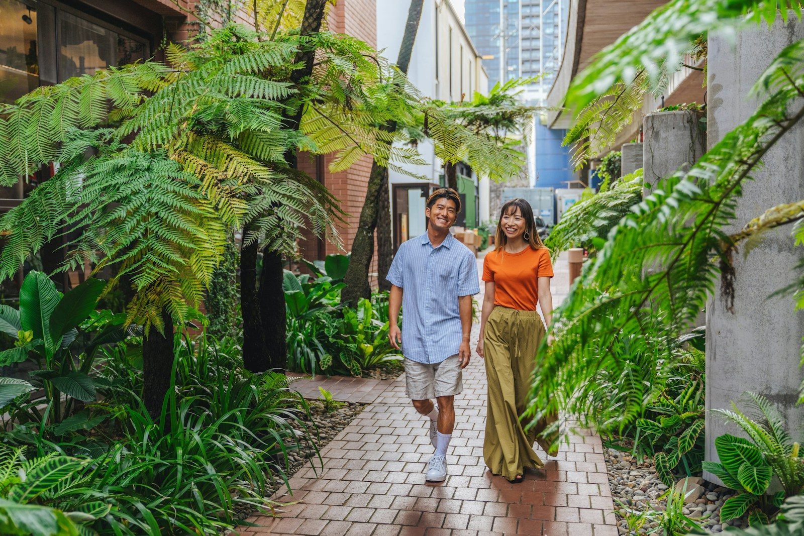 A man and a woman walking along a brick path in a lush garden